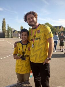 A learner and a staff member in matching yellow football shirts