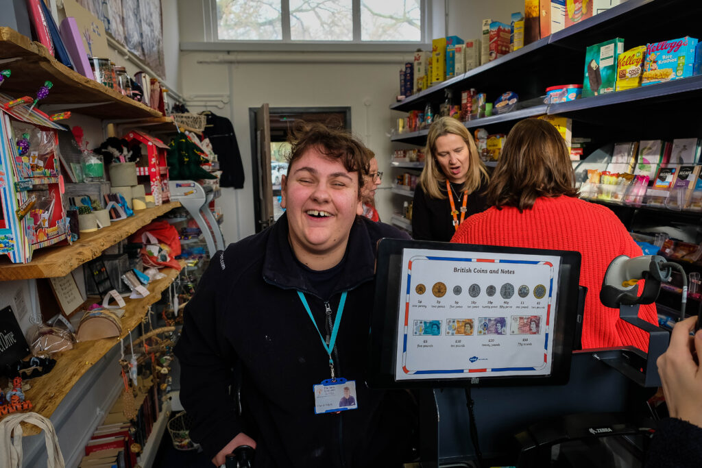 A young woman, smiling at the camera, standing in the college's very own Tesco store