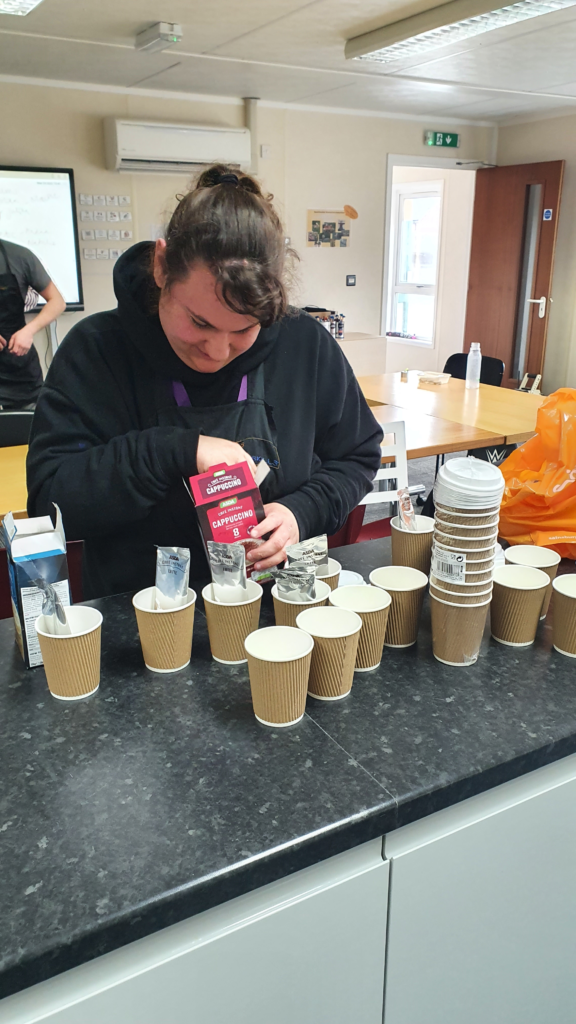 A young learner preparing many takeaway cups of tea and coffee