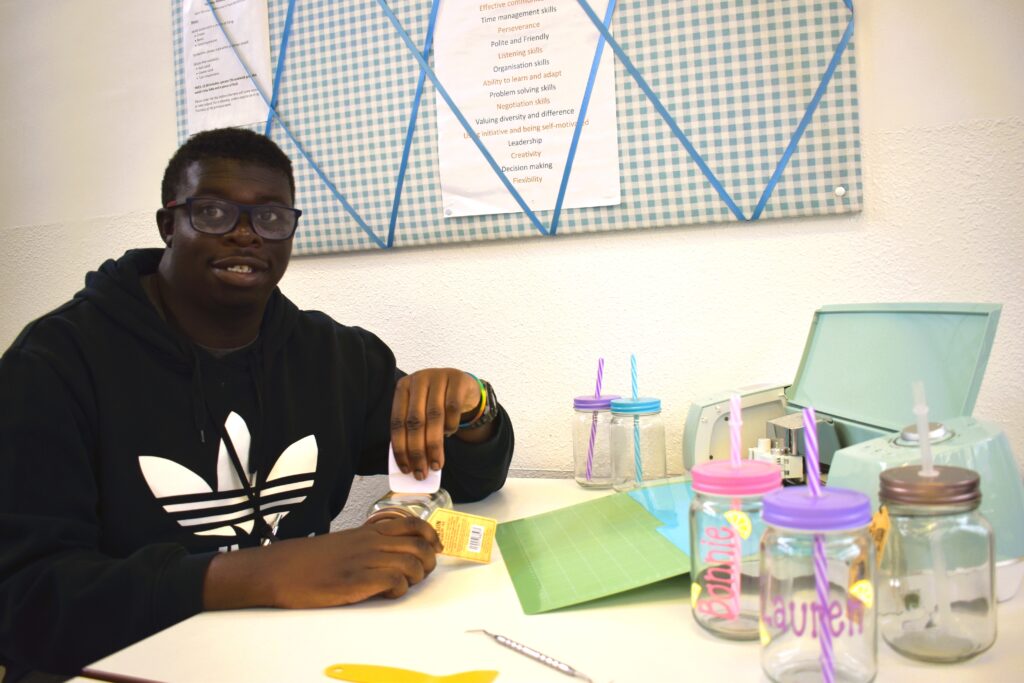 A young learner making colourful craft products as part of his art enterprise group