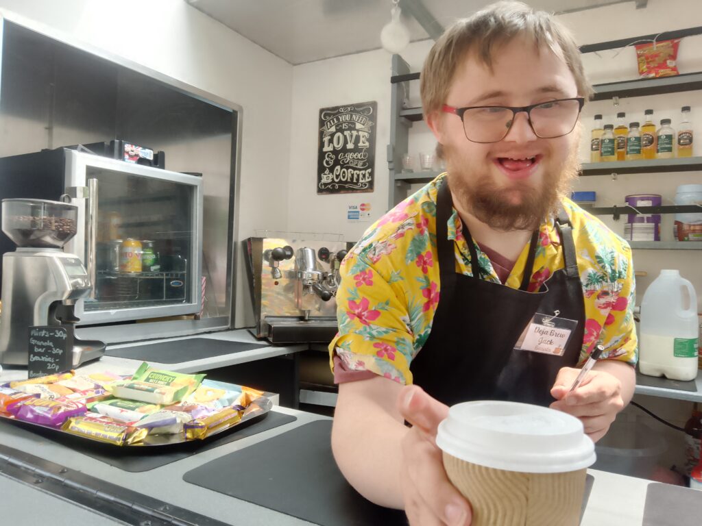 A male learner, proudly serving coffee from the college's mobile catering cart