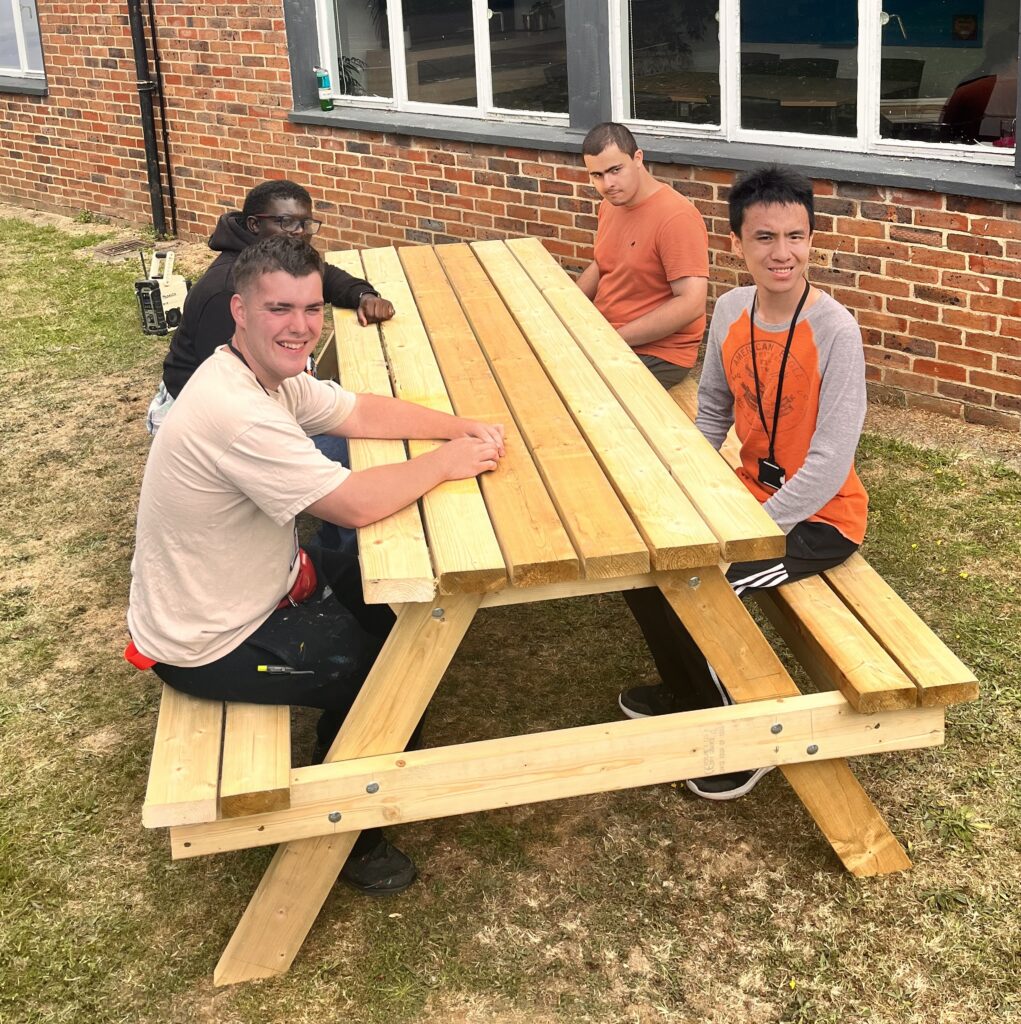 Group of learners sitting at a picnic bench that they have constructed in their carpentry enterprise group