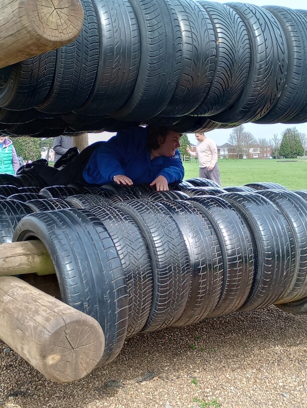 A young learner climbing through a tyre obstacle on an assault course