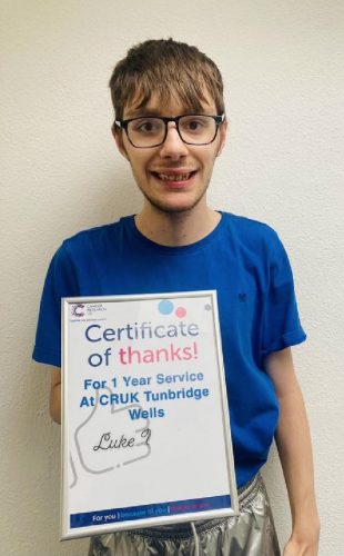 Young man smiling to the camera, holding a certificate